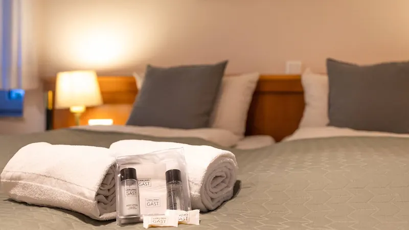 Gerollte Handtücher und Pflegeset auf dem Doppelbett