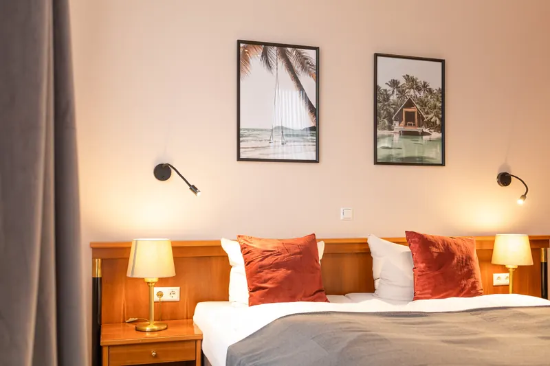 Doppelzimmer im Hotel am Park Waltrop mit Holzkopfteil, rostroten Samtkissen, Nachttischlampen und Leseleuchten