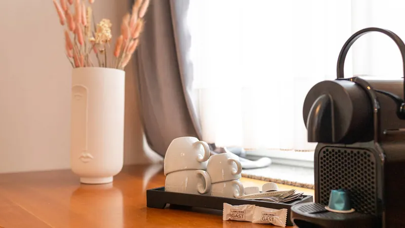 Kaffeestation mit Kapselmaschine, Tassen und Trockenblumen im Doppelzimmer