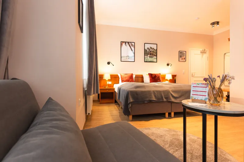 Geräumiges Doppelzimmer mit Sofa, Beistelltisch und Blick auf das Doppelbett
